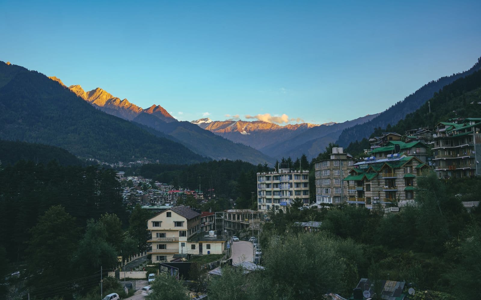 Manali town beneath sunset-lit Himalayan peaks, Himachal Pradesh