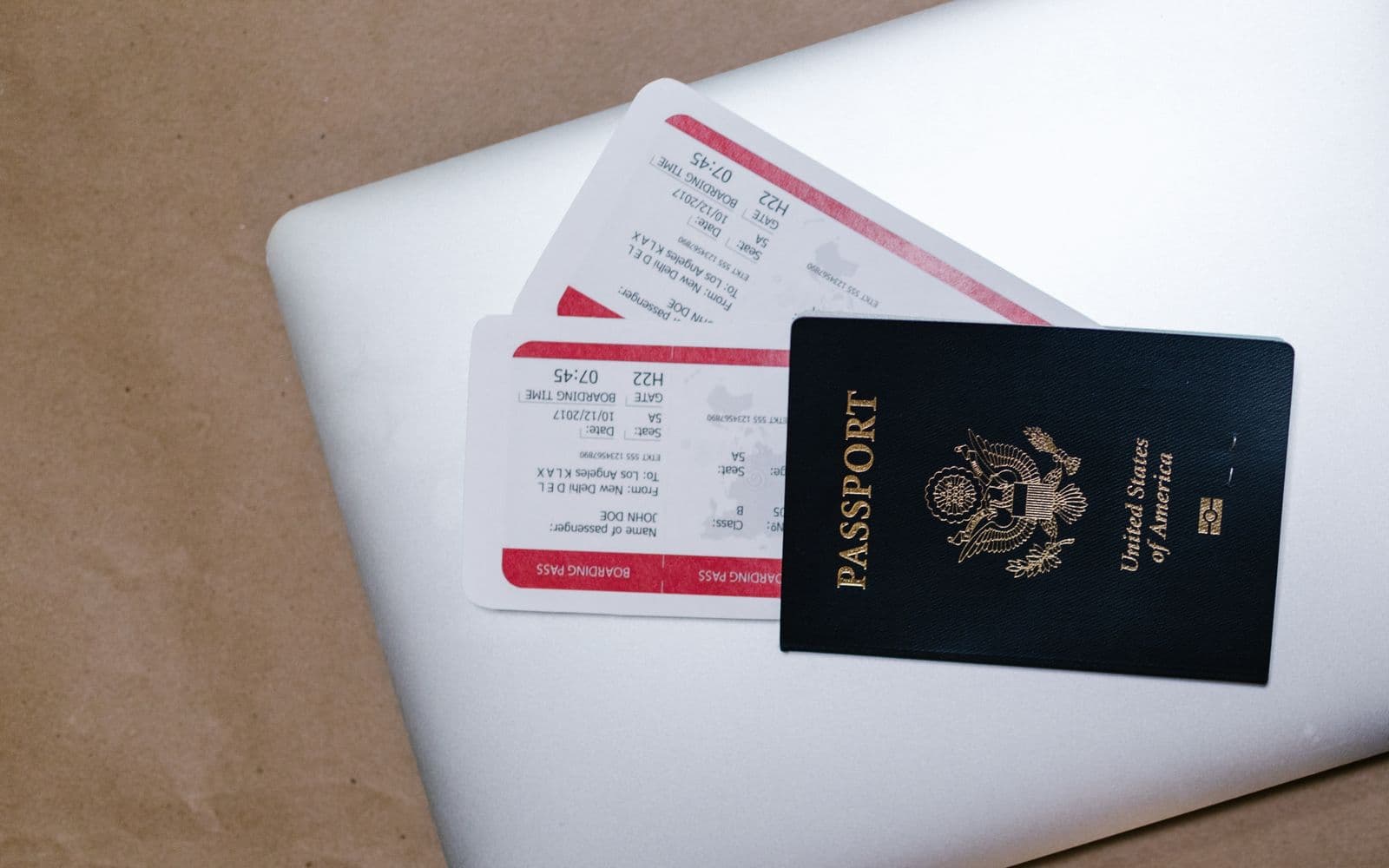 Passport and boarding passes resting on a laptop before a trip