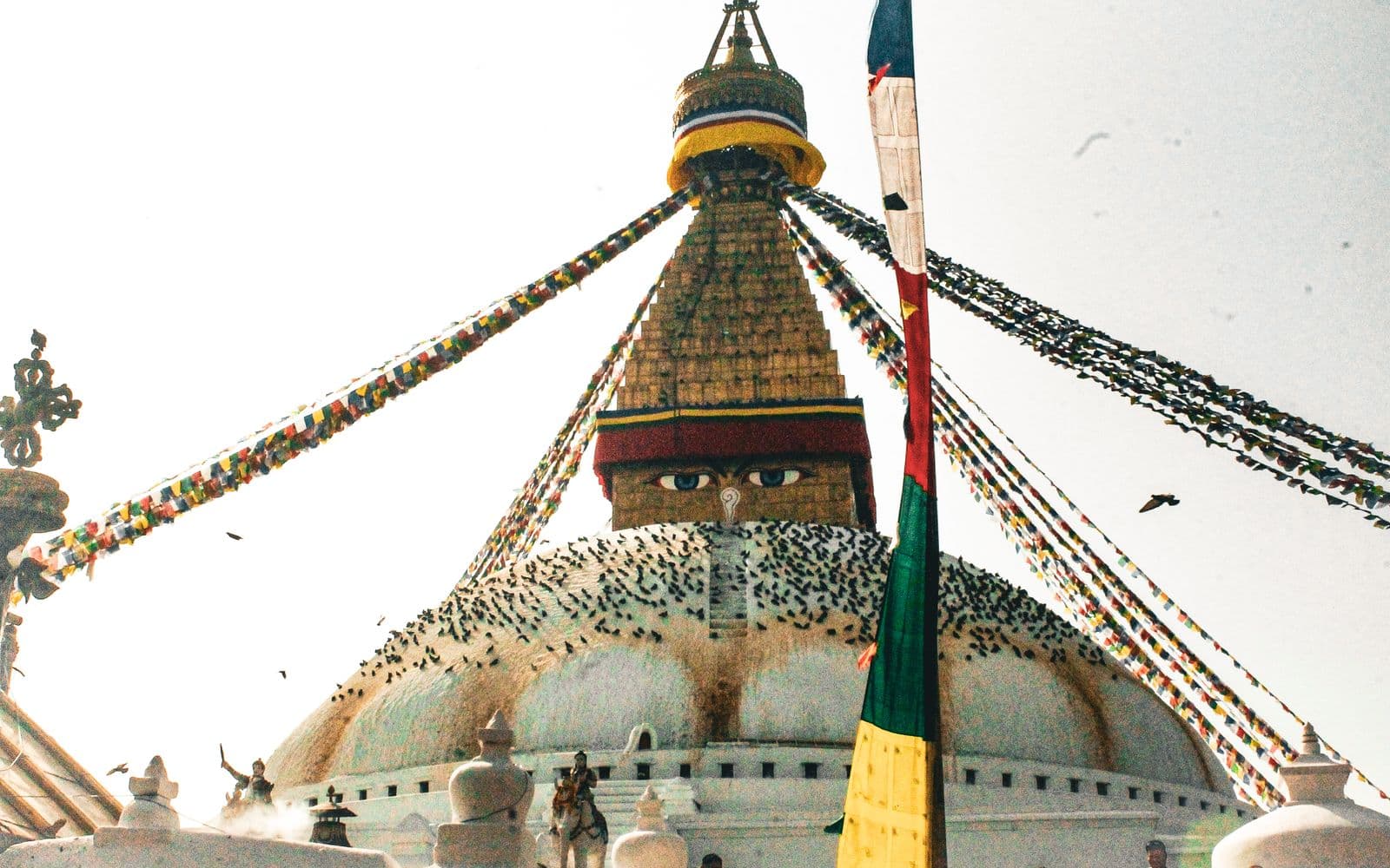 Boudhanath Stupa in Kathmandu draped with colourful prayer flags under a clear sky